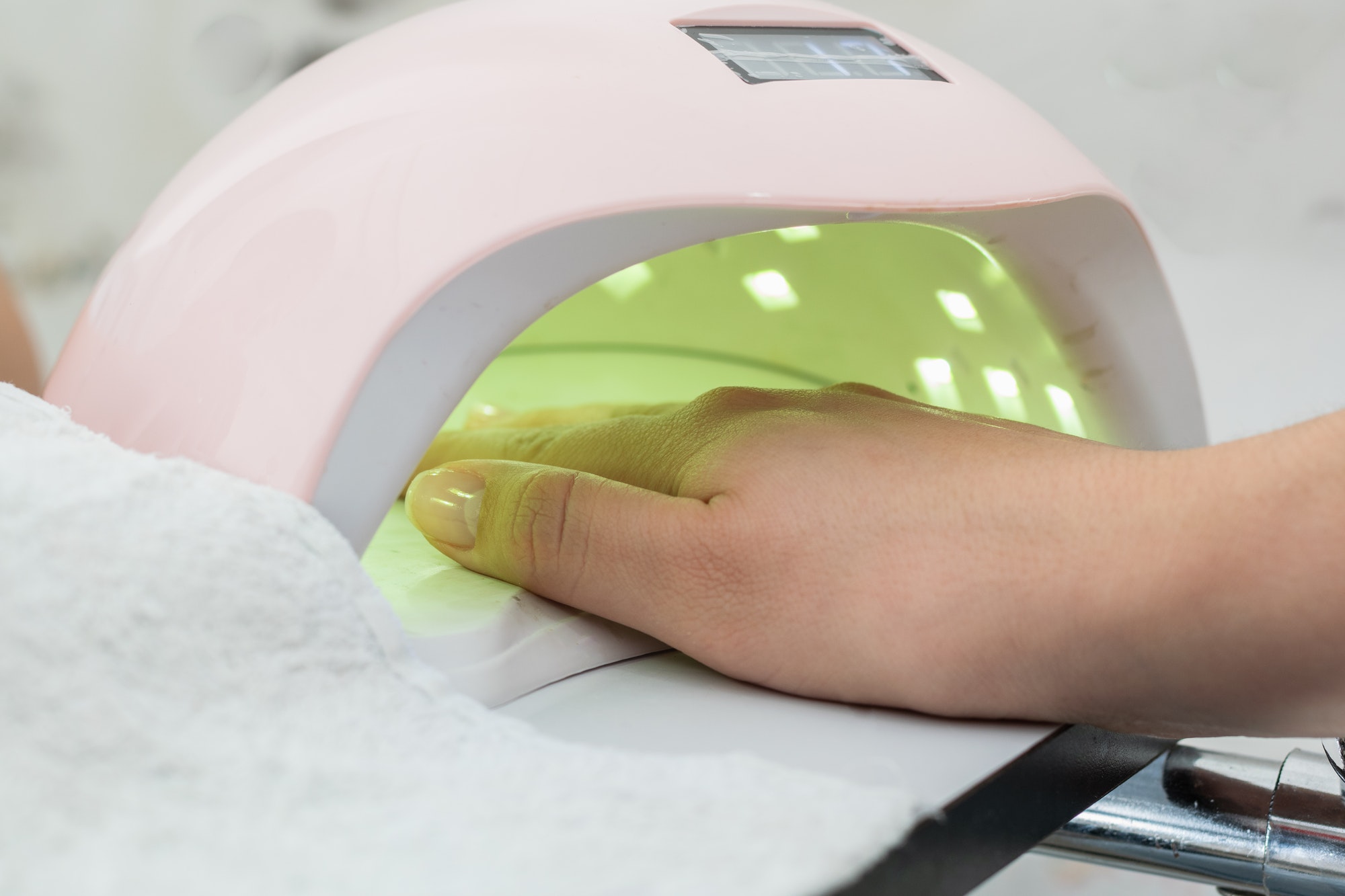 close-up of a latina girl's hand inside a 48 watt led nail lamp for semi permanent acrylic gel.